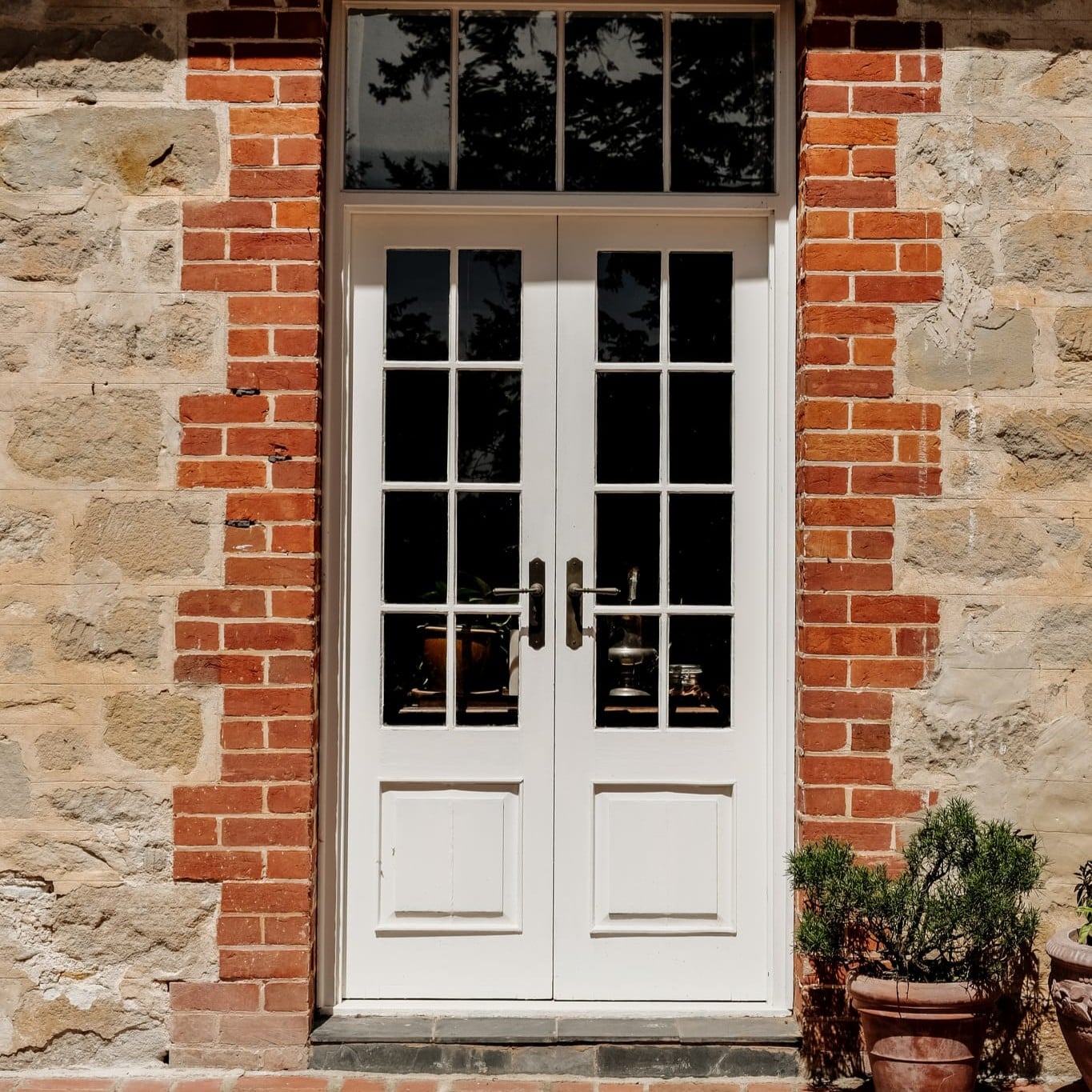 Bluestone cottage frontage with white french doors and brass lever handles