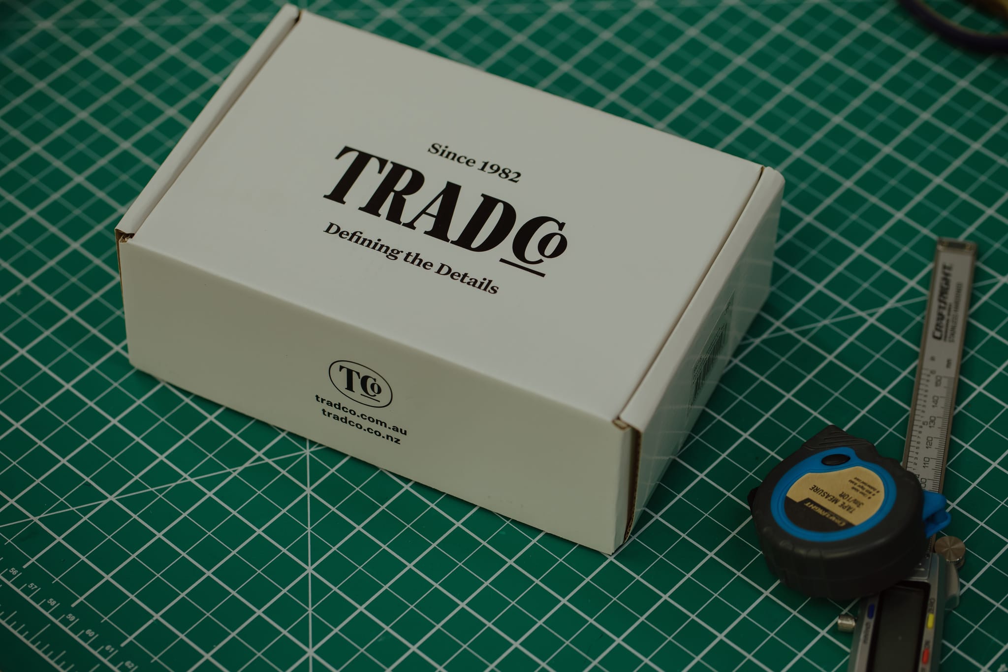 A TradCo box on the workshop bench beside a tape measure and callipers