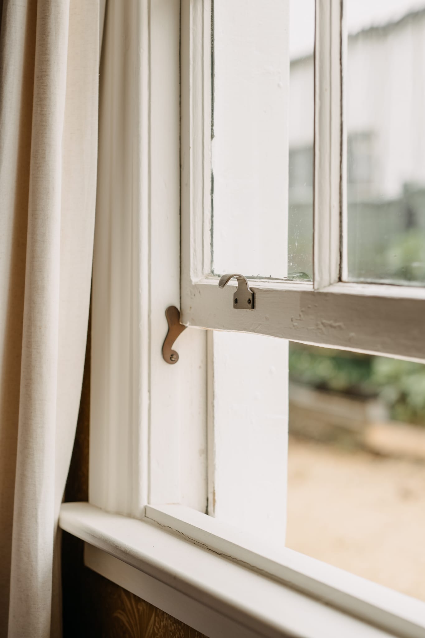 Brass sash drop holding a timber sash window open