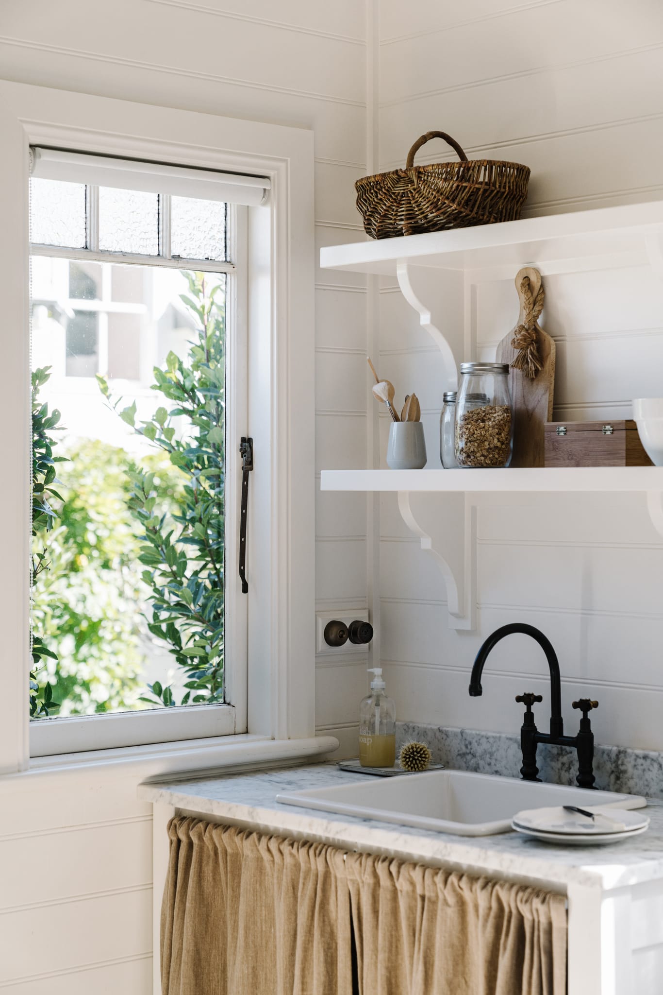 Sidemount casement stay on a white timber casement window above a laundry sink
